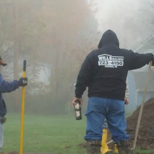 Crew member in a Wills Builders 723-4190 hoodie on a foggy morning job site